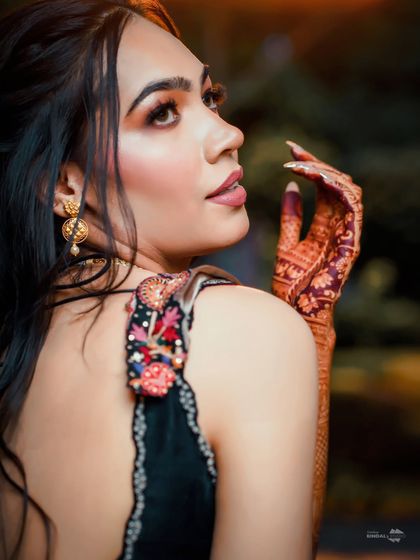 A stunning close-up of the bride, showcasing her intricate henna and elegant jewelry. Her confident expression and the beautiful lighting make this a captivating portrait.