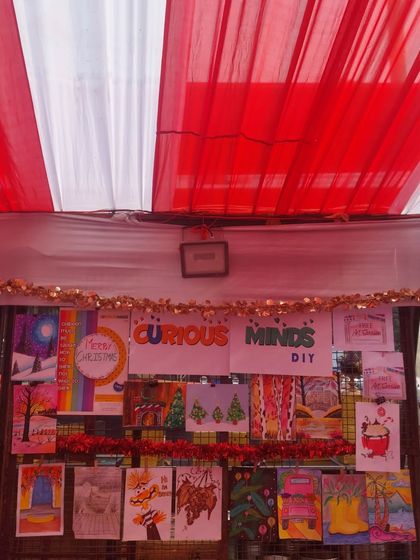 The "Curious Minds DIY" banner and a wall of inspiring art at my Christmas-themed stall. The red and white decor added to the festive atmosphere.