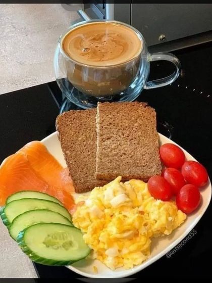 A simple yet elegant breakfast of scrambled eggs, smoked salmon, and brown bread, served with coffee.