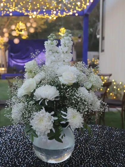 A beautiful white floral centerpiece on a sequined black tablecloth, adding a touch of elegance to the party's decor.