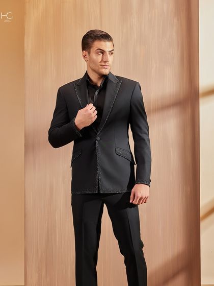 A full-length view of the dazzle-stitch jacket. The all-black look is given a touch of glamour through the carefully applied trim on the lapels and pockets.