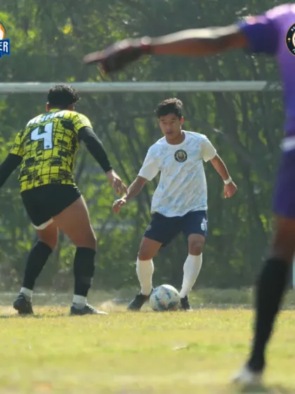 A player dribbles with close control, navigating through a tight space on the pitch.