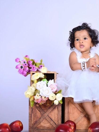 A collage of a baby girl in a white dress with apples and flowers.