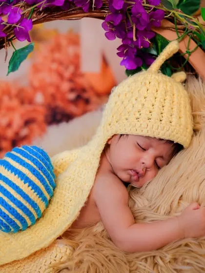 This newborn is sleeping soundly in our snail costume, surrounded by a wreath of purple flowers. The combination of textures and colors makes for a beautiful portrait.