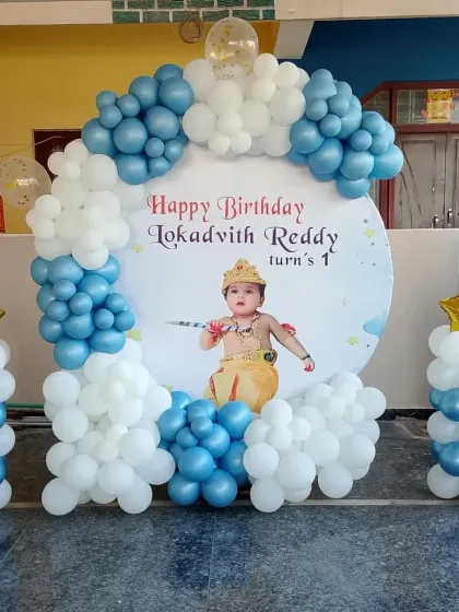 A Little Krishna themed first birthday with a custom photo backdrop and a blue and white balloon frame.