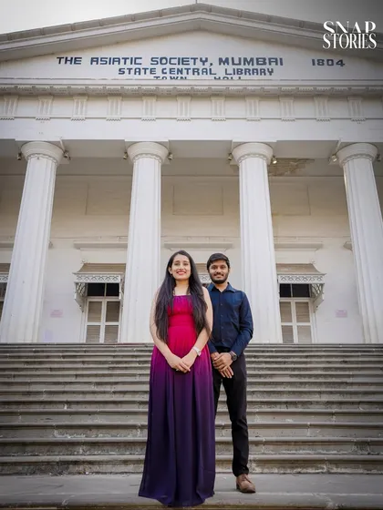 A full-frame shot of a couple standing before the iconic pillars of The Asiatic Society Library in Mumbai, a popular location for a classic and grand pre-wedding photoshoot.