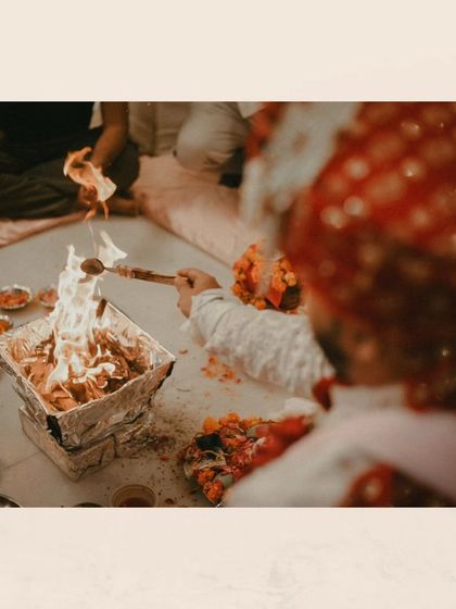 A detail shot of the havan (sacred fire), a central element of a Hindu wedding ceremony, with the groom making an offering.