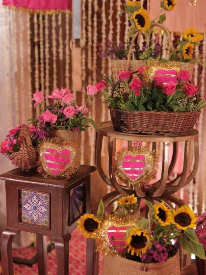 A close-up of the decor, featuring pink roses and sunflowers in baskets, accented with gota patti hearts.