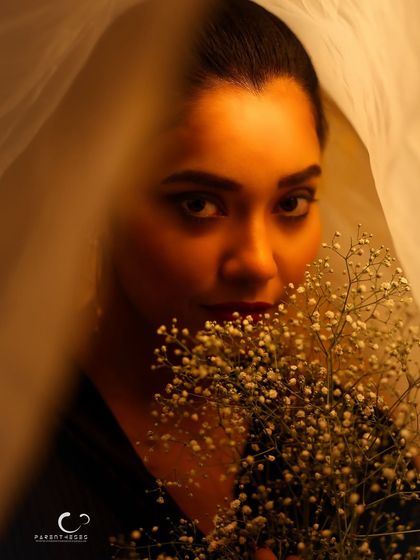 A playful and mysterious peek from behind the flowers and veil. Her eyes are the focal point, drawing the viewer in.