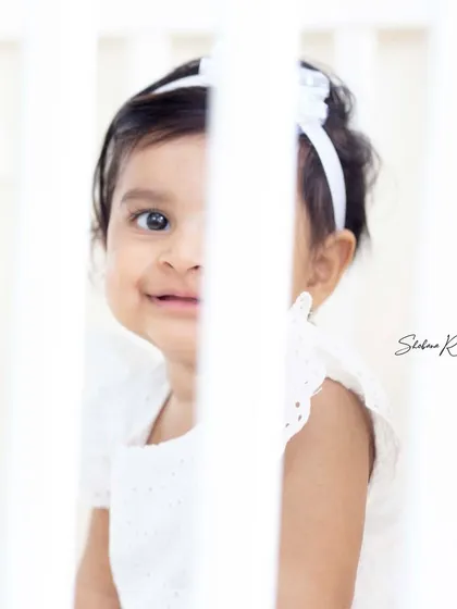 A playful peek-a-boo moment through the crib bars. I love finding creative angles to capture your baby's personality.