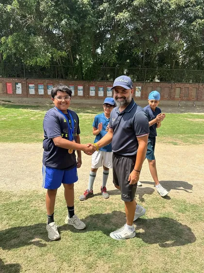 A young player smiles as he receives his medal from the coach. Celebrating achievements is a core part of our academy's culture.