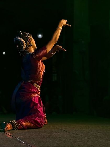 A kneeling pose of offering, with the temple architecture visible in the background.