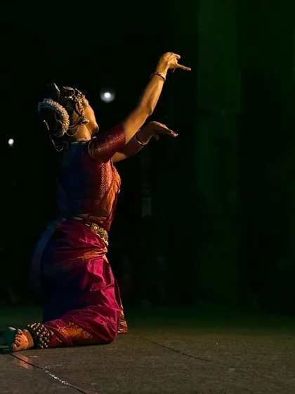 A kneeling pose of offering, with the temple architecture visible in the background.