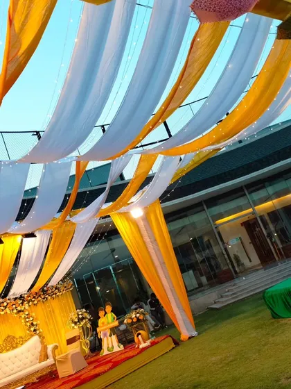 A view of the Haldi canopy from below, showing the interplay of yellow and white drapes with fairy lights against the sky.