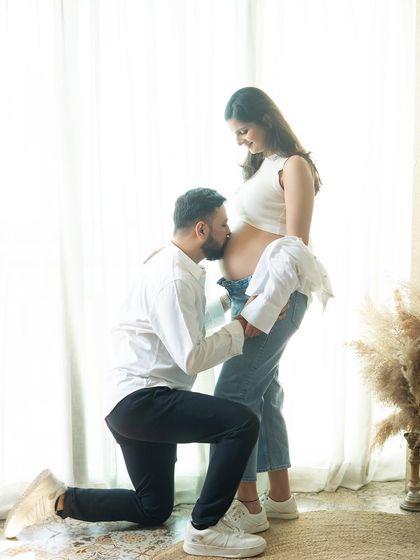 A kiss for the baby. This is such a loving and classic pose for a couple's maternity shoot, filled with anticipation for the little one's arrival.