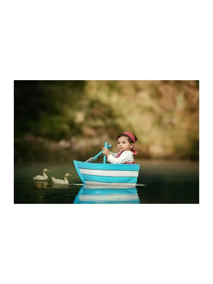 Here, the little captain looks determined, ready to row his boat. Capturing these different expressions is part of the fun in a themed baby photography session.