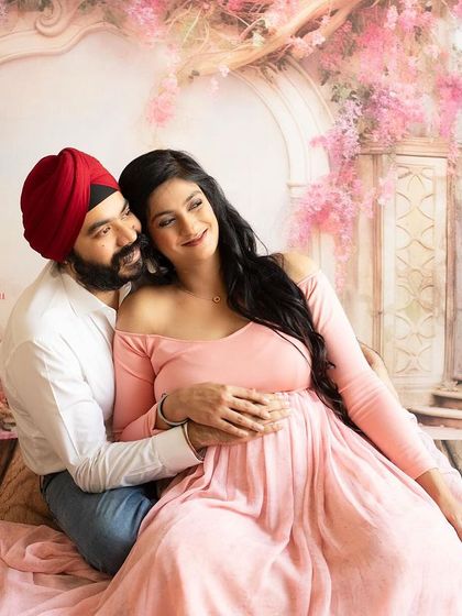 A fairytale moment for the parents-to-be. This studio setup with a beautiful floral backdrop creates a romantic and whimsical setting for a couple's maternity photoshoot.