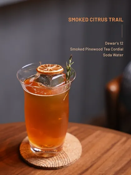 The Smoked Citrus Trail, featuring Dewar's 12 and a smoked pinewood tea cordial. This drink offers bright, smoky notes with a clean soda water finish.