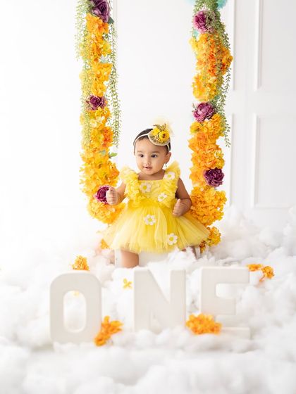 The complete whimsical setup for a first birthday, with the "ONE" letters nestled in the clouds. The yellow floral theme is bright, cheerful, and perfect for a celebration.