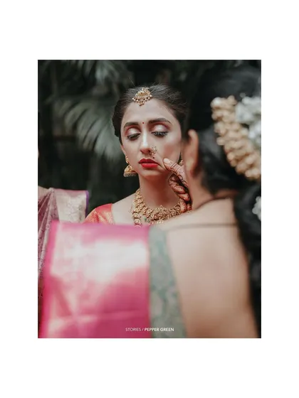 A behind-the-scenes moment of the bride getting her makeup touched up, a quiet moment of preparation.