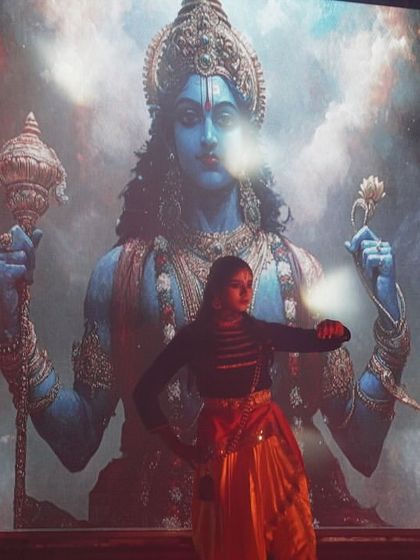 A dancer performs in front of a large digital screen displaying the cosmic form of Lord Vishnu. This fusion of traditional dance and modern visuals is a hallmark of our productions.