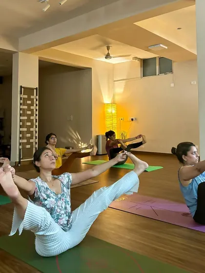 A student balances in Ubhaya Padangusthasana, showcasing the core strength and hamstring flexibility developed through consistent practice.