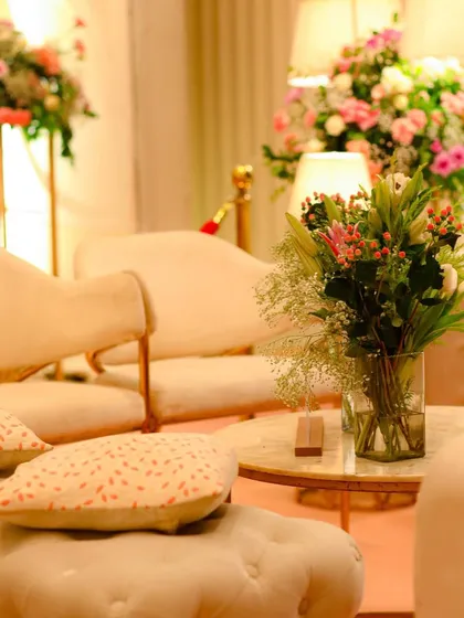 Soft textures and earthy tones create a warm and inviting lounge area. Plush cream seating with patterned cushions and fresh floral arrangements make for a comfortable and elegant space.