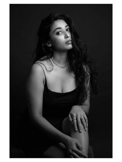 A gentle and contemplative black and white portrait. The lighting is soft, and the pose is natural, creating an image that feels both intimate and sophisticated.