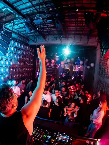 A shot from behind the decks at Roxy, with my hand up, connecting with the packed dance floor.