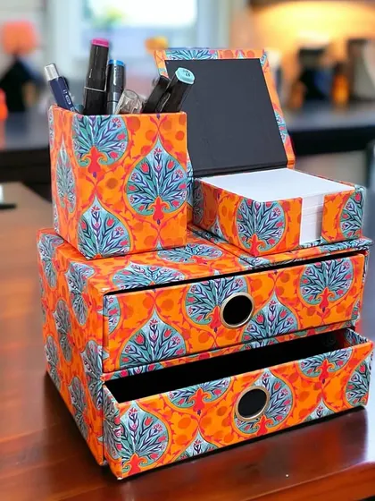 Our Sia desk set brings a pop of color to your workspace. This organizing set includes a two-drawer chest, a pen stand, and a memo box, all in a vibrant orange print.