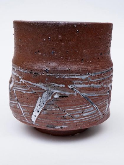 This teabowl has a rough, earthy texture with white slip creating a stark, abstract pattern. It's a piece that holds emotion and is more than just a bowl.