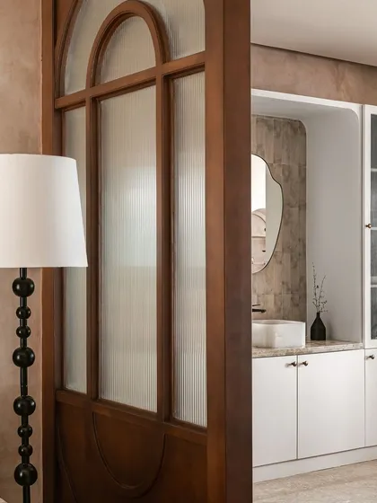 This view shows the wooden and fluted glass partition that separates the living and dining areas, with a glimpse of the wash basin unit beyond. This partition adds privacy without blocking light.