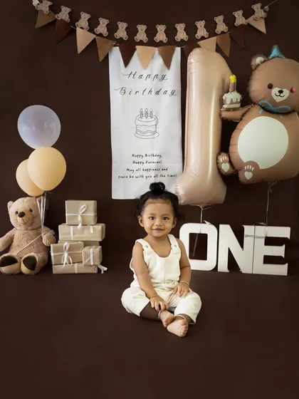 A sweet, seated portrait of the birthday boy in his adorable outfit, surrounded by a warm, earthy-toned birthday set.