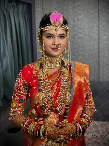 A bride in a traditional red Paithani saree, complete with the 'bashing' headwear for the wedding ceremony.
