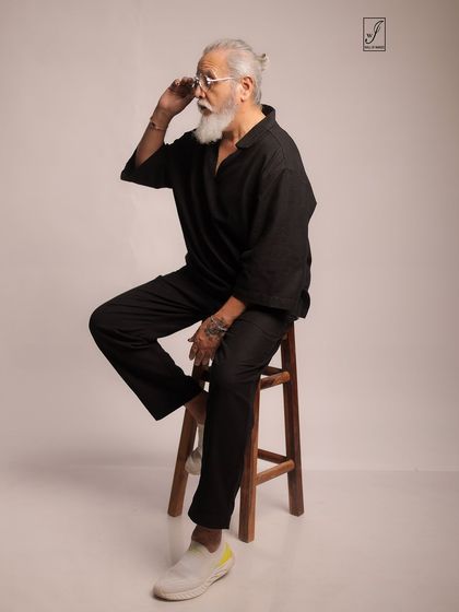 Adjusting his glasses, the model adds a touch of personality and intellect to this lifestyle portrait.