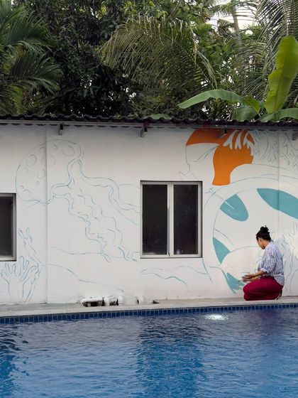 Another angle of me working on the poolside mural, sitting at the edge of the pool to paint the lower sections. This shows my hands-on approach to every part of the painting process.