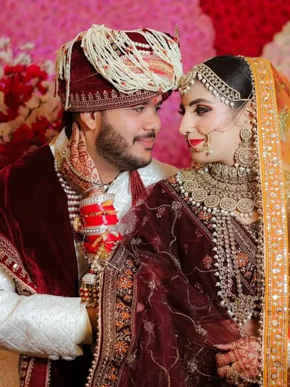 A beautiful portrait of the couple looking at each other. This shot captures the love and connection between them on their wedding day, set against a colorful floral wall.