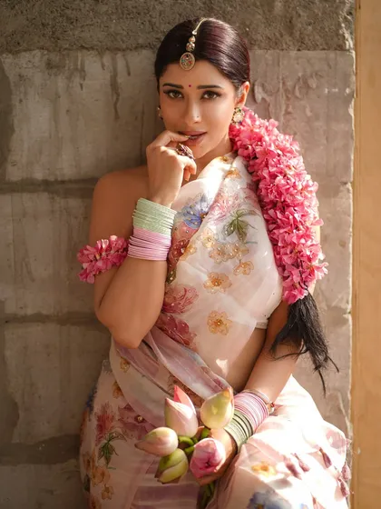 A slightly mischievous and playful look from Nyra Banerjee. The focus is on the expressive eyes and the delicate hand-to-face gesture, drawing attention to the makeup and jewelry.