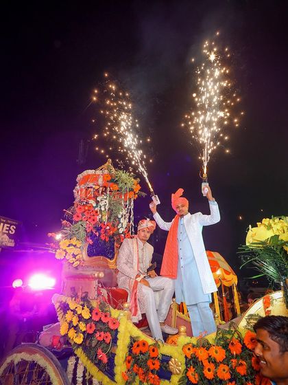 The energy and excitement of the Baraat (groom's procession), with friends holding up sparklers on a decorated carriage.