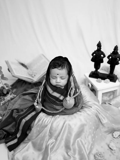 The contrast in this black and white image beautifully highlights the textures of the fabrics and the serene expression of the baby.