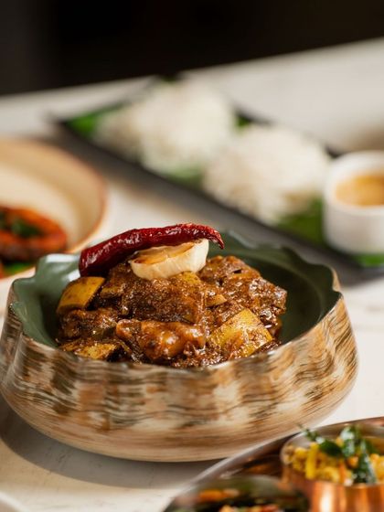 A close-up of the famous Kodava pandi curry (pork curry). This iconic dish is known for its dark, rich gravy flavored with kachampuli, a special vinegar from Coorg.