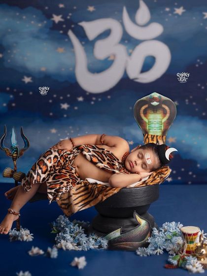 A sleeping little Shiva, looking peaceful and divine, rests against a shivling under a starry sky.