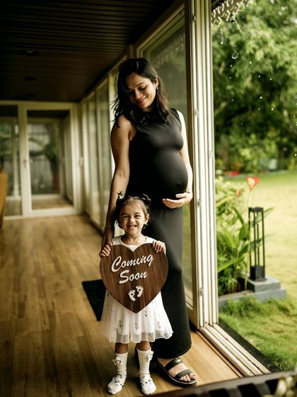 A beautiful full-length portrait of a mother and daughter sharing their happy news. The daughter's proud smile as she holds the announcement sign is a precious memory.