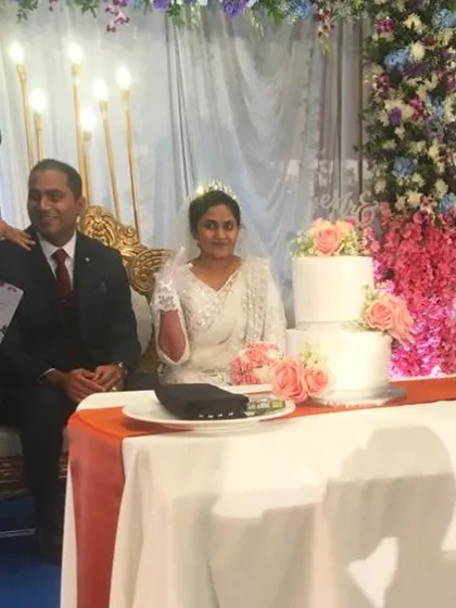The bride and groom at their reception with the classic three-tier wedding cake I created for them. Even with last-minute orders, I ensure every cake is a worthy centerpiece for such an important occasion.
