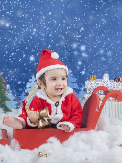 This little Santa is ready to deliver presents, sitting in his sleigh surrounded by gifts.