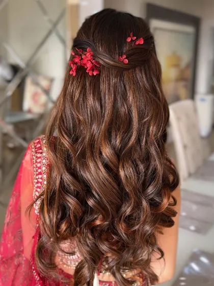A back view of the engagement hairstyle, showing the cascading waves and the pop of red from the floral accessories.
