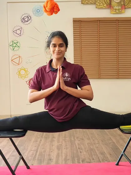 We help you push your boundaries safely. This student demonstrates incredible flexibility and balance in a full split (Samakonasana) supported by two chairs, a testament to dedicated practice and advanced training techniques.