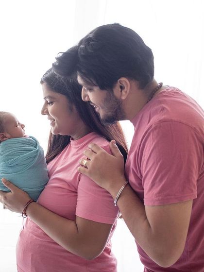 A side profile of a new family of three. This angle provides a lovely, intimate view of the parents admiring their newborn baby.