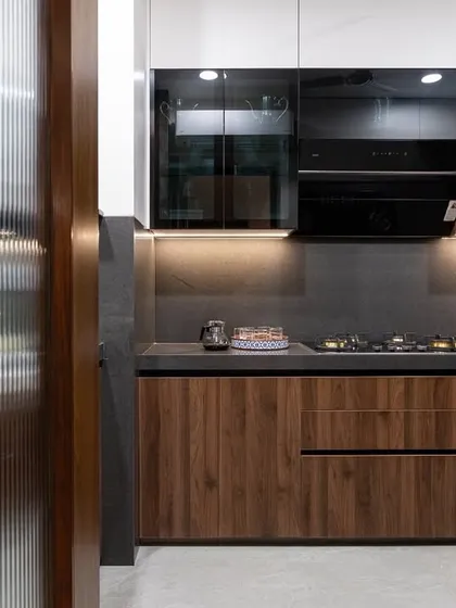 A beautiful kitchen combining wood-finish lower cabinets with white and black glass upper cabinets. The fluted glass door adds a textural element to the entrance.