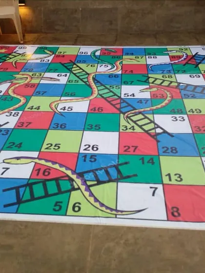 Another view of the giant snakes and ladders game mat laid out and ready for play. It's a colorful and engaging activity for kids and families.